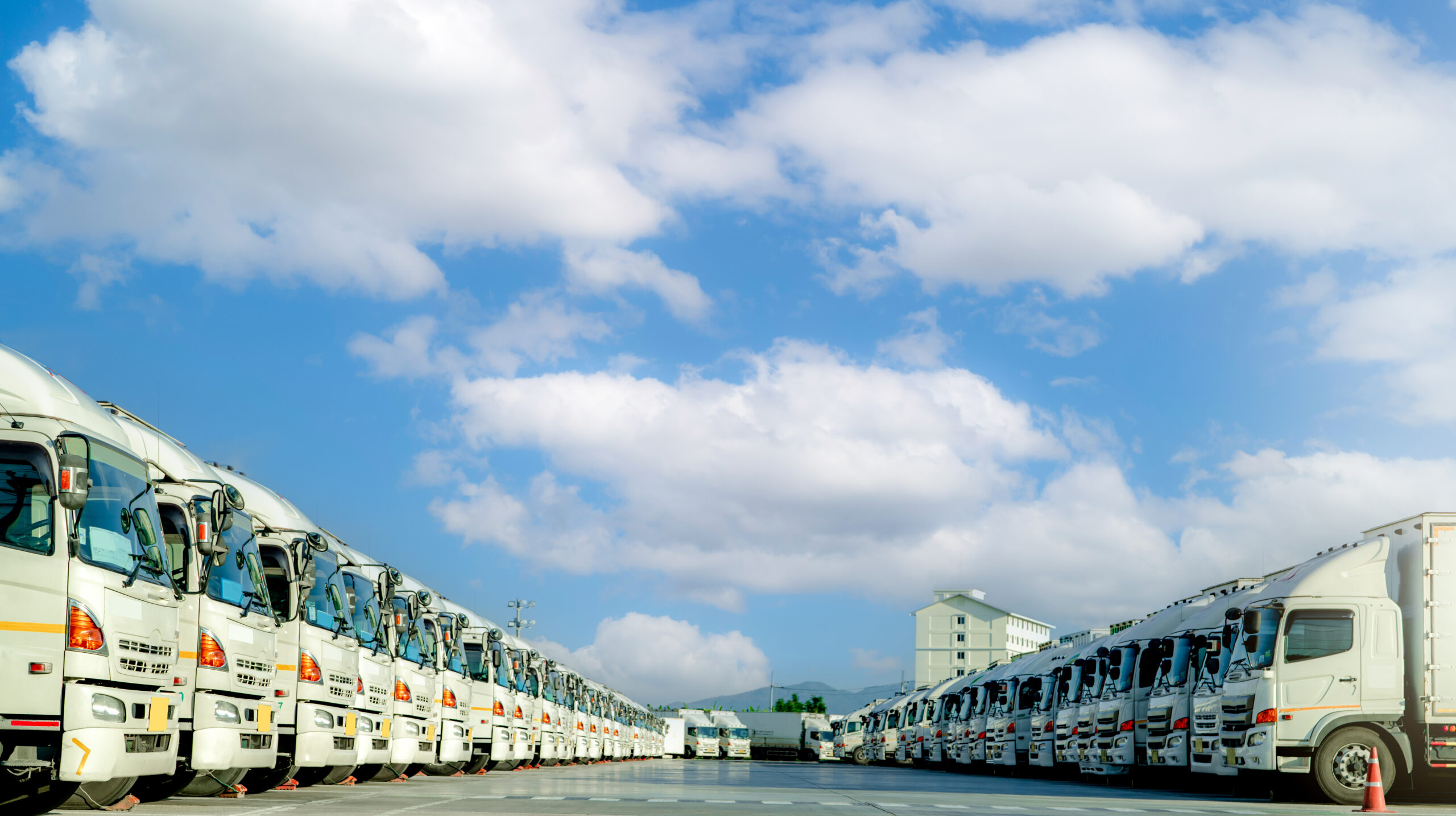 Fleet of trucks parked at parking lot yard of delivery company. Truck transport. Logistic industry. Freight transportation. Truck leasing. Commercial truck for delivering goods from warehouse. Cargo